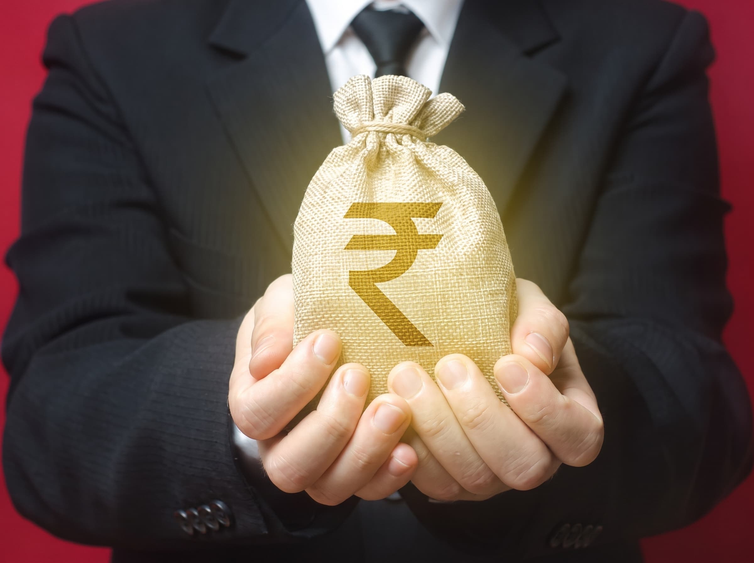Hands offering a money bag marked with the rupee symbol
